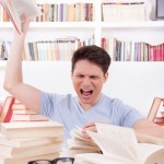 angry student surrounded by books throws a book